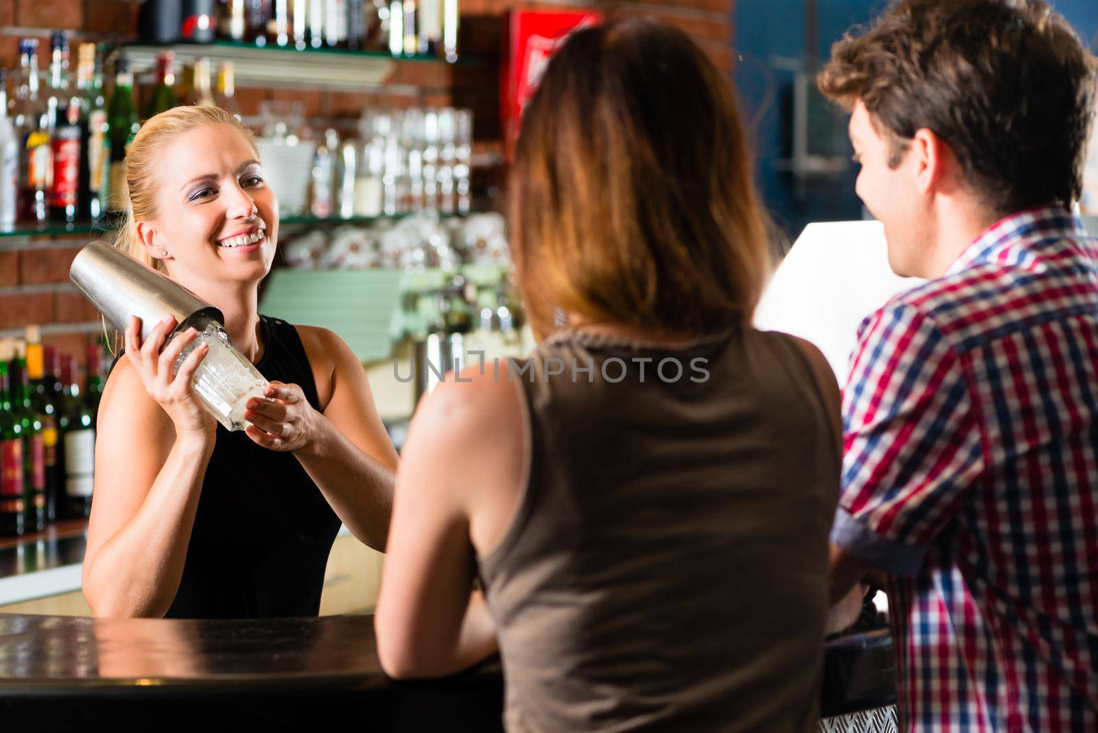 Young people or couple having a date in a club or bar, the bartender mixes a drink