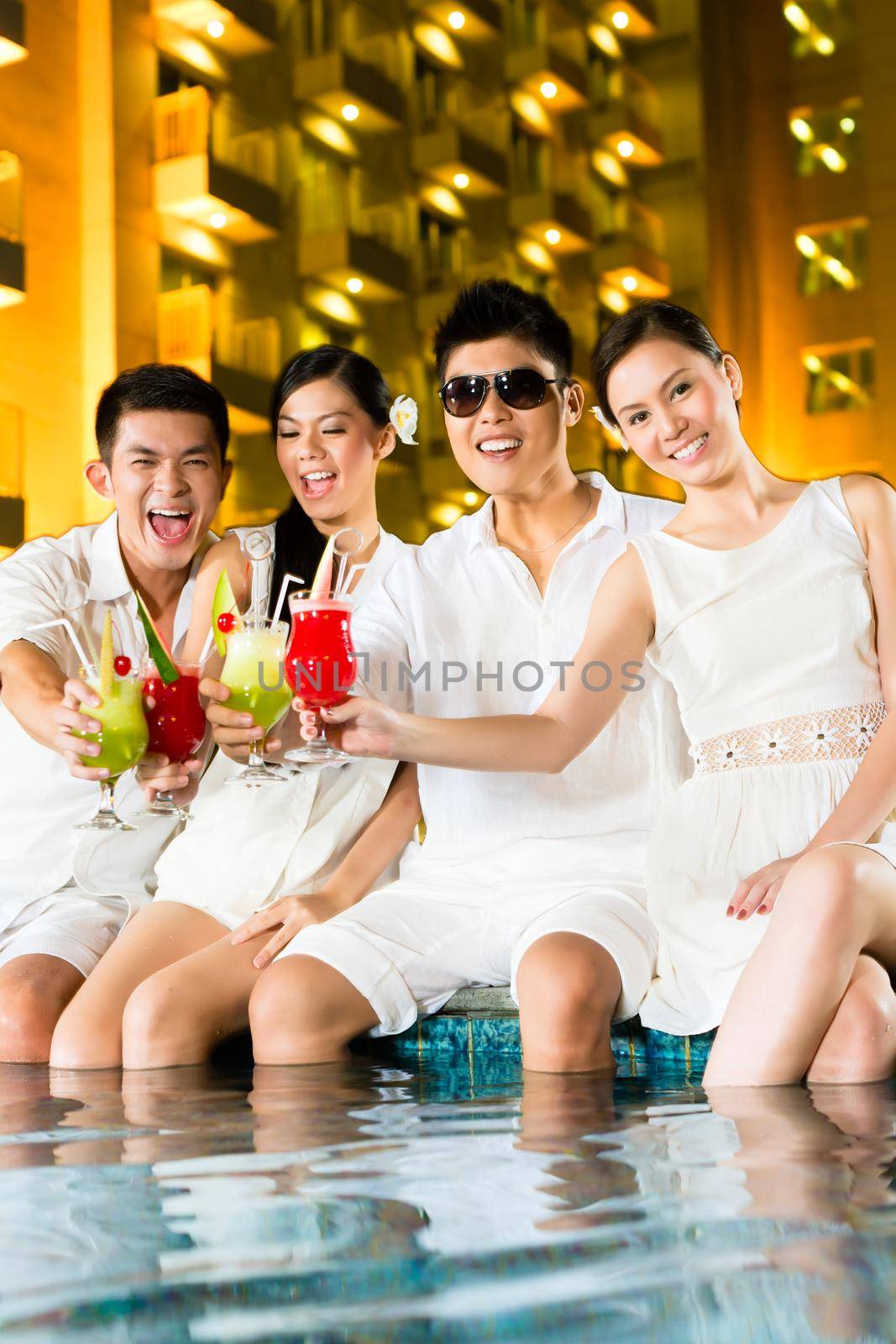 Chinese couples drinking cocktails in hotel pool bar by Kzenon