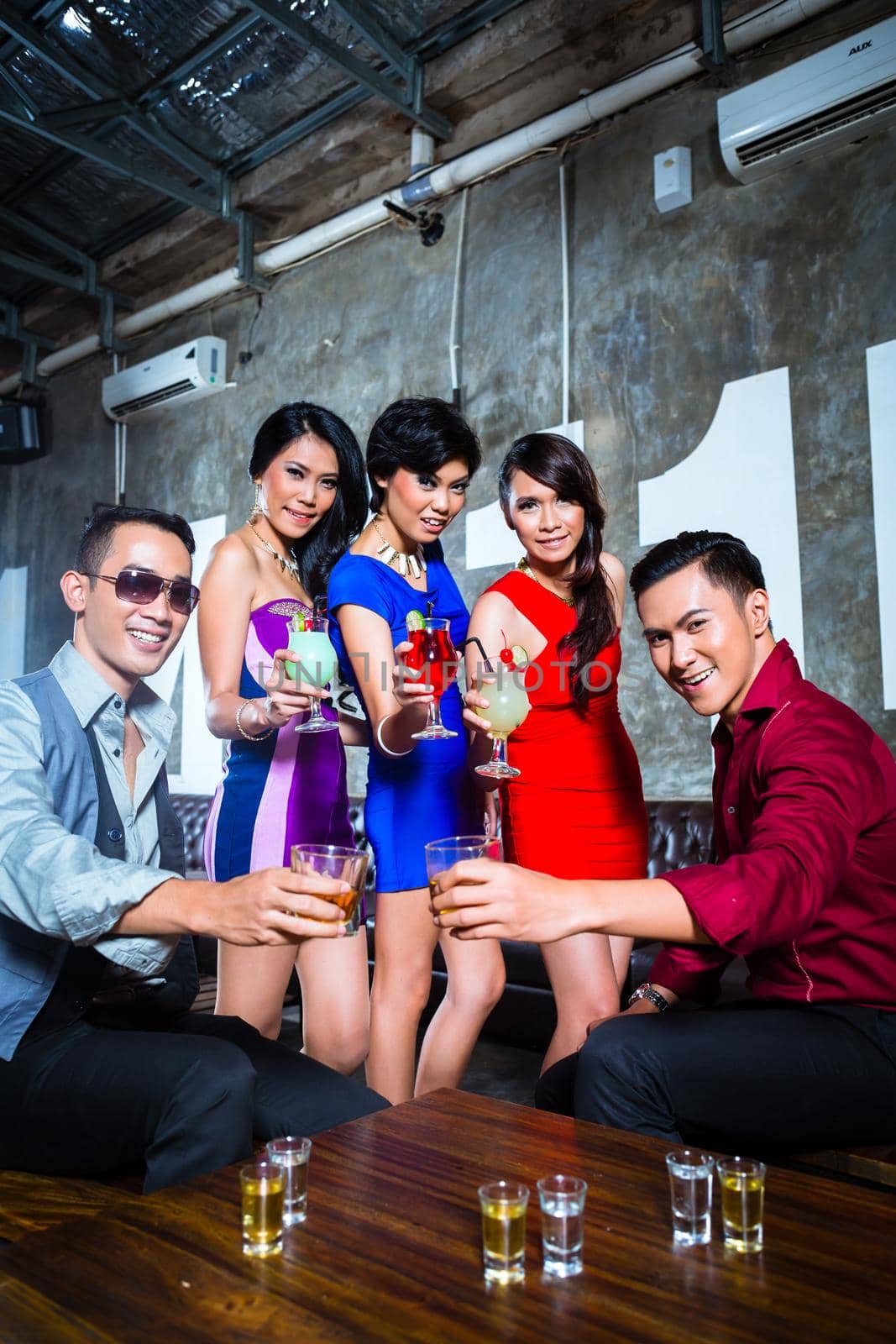 Asian young and handsome group of party people or friends drinking cocktails and shots in fancy night club