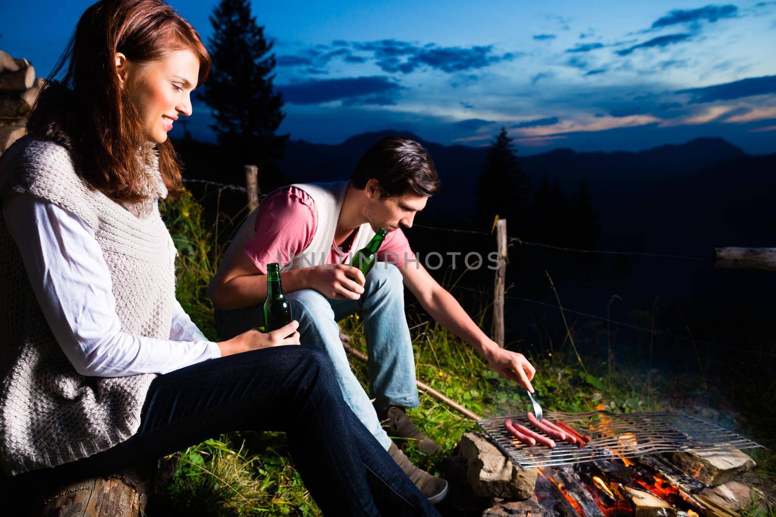 Alps - Couple at campfire in mountains by Kzenon