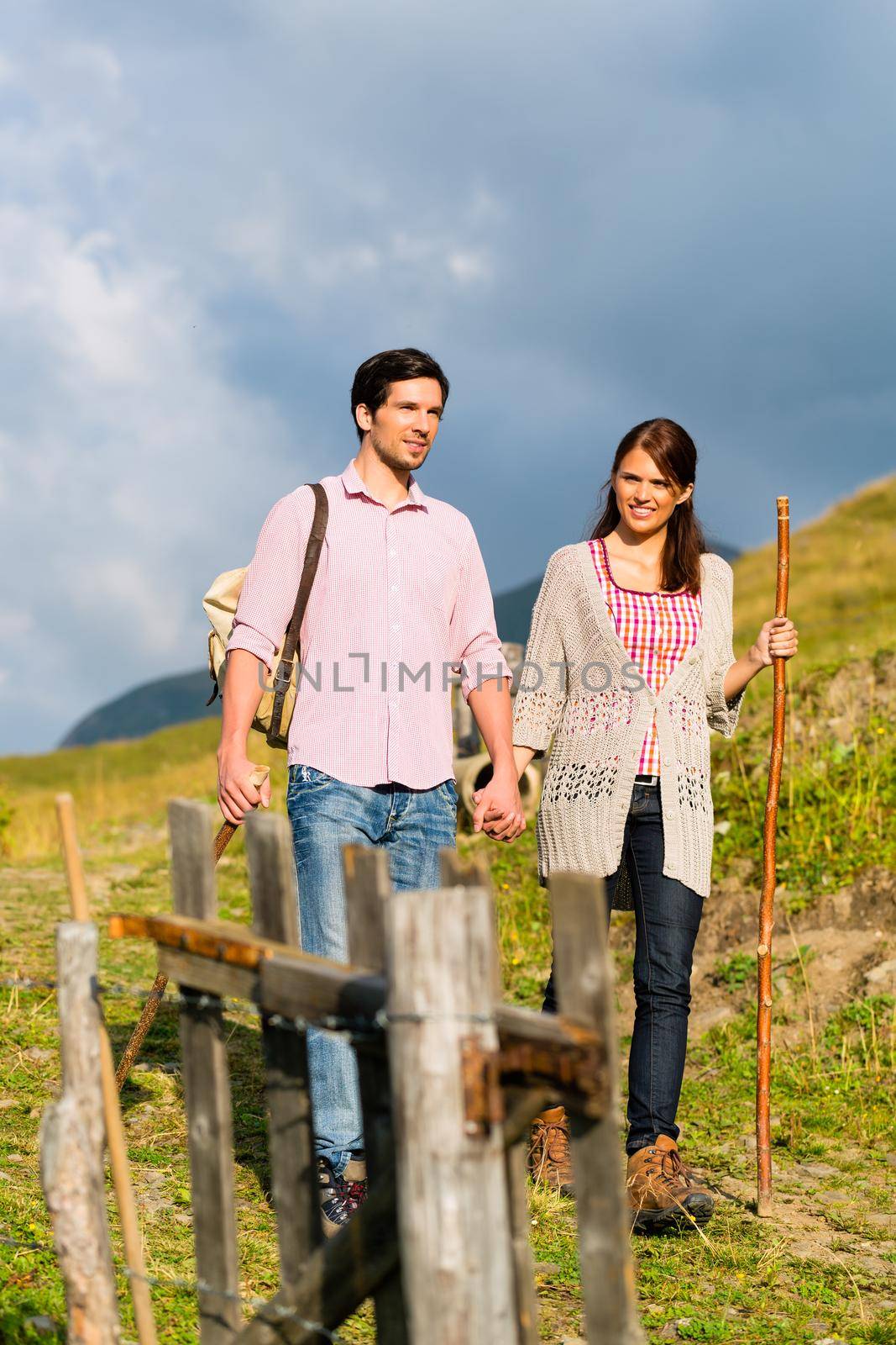 couple of man and woman hiking on mountain summit or alpine grassland in the Bavarian Alps, enjoys the panorama in the leisure time or in vacation