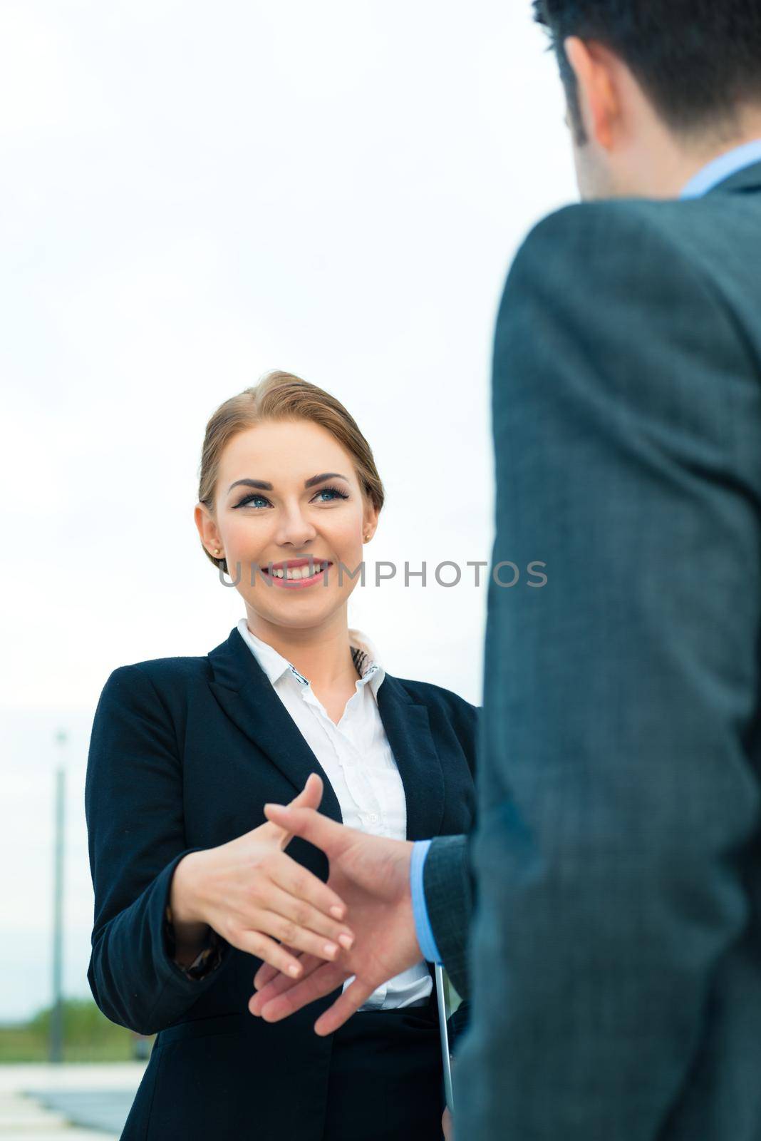 Business handshake - two businesspeople shaking hands to conclude deal or agreement