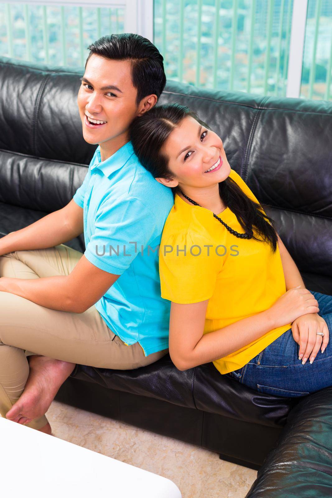 Young Asian couple on sofa or couch by Kzenon