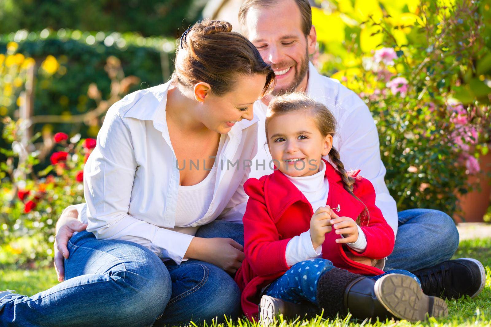 Family with mother, father and daughter together in the garden meadow