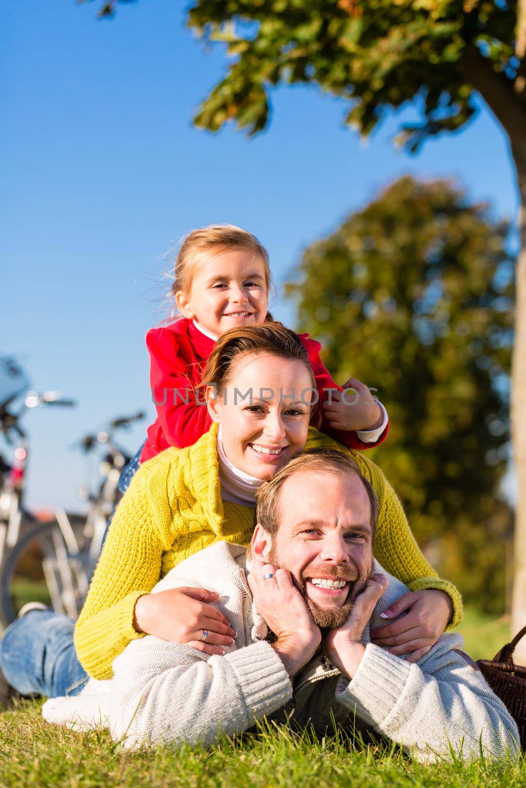 Family with bicycle in park in fall by Kzenon