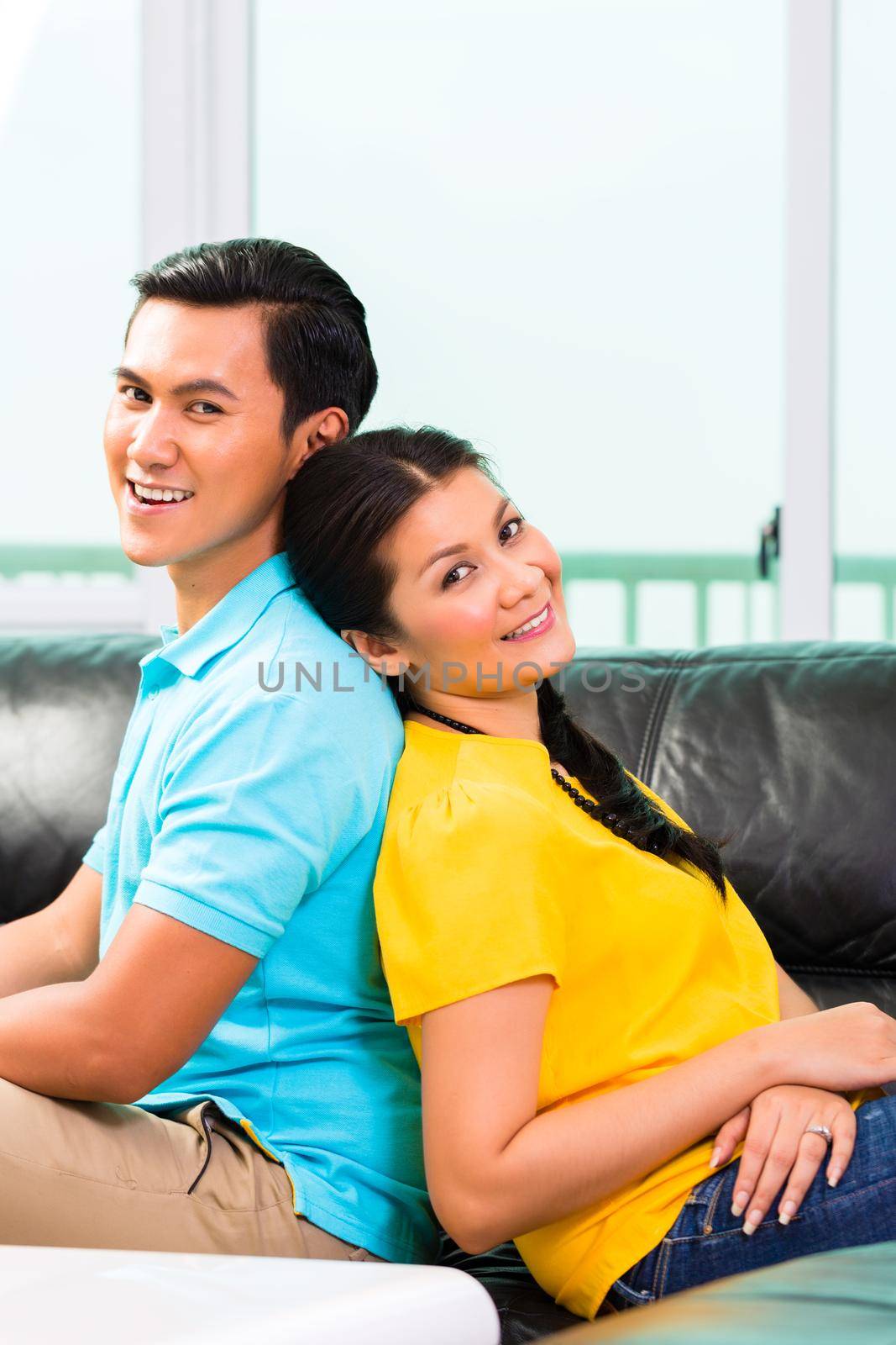 Young Asian handsome couple having long-term relationship sitting on sofa or couch