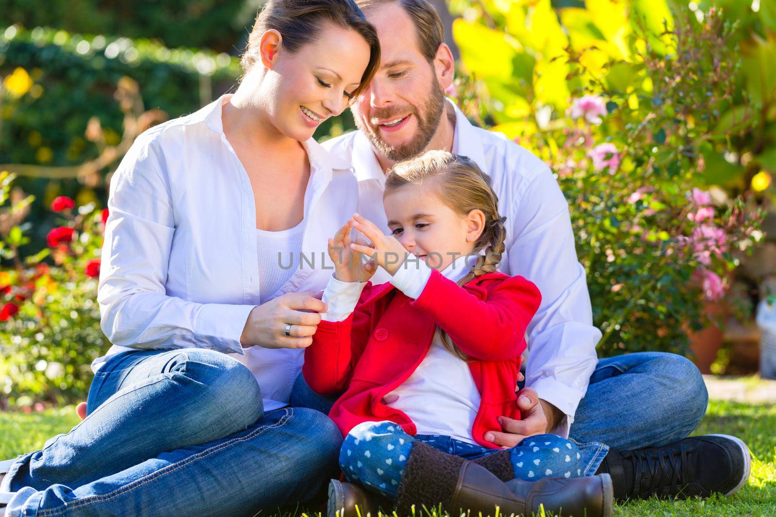 Family with mother, father and daughter together in the garden meadow