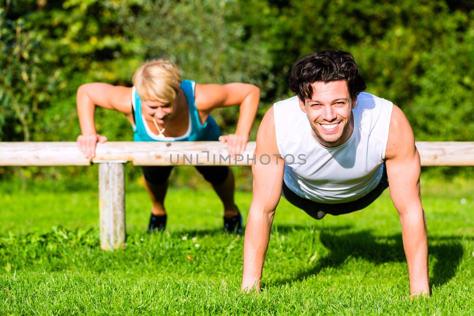 Young man and woman or personal trainer exercising pushups in City Park for sport fitness