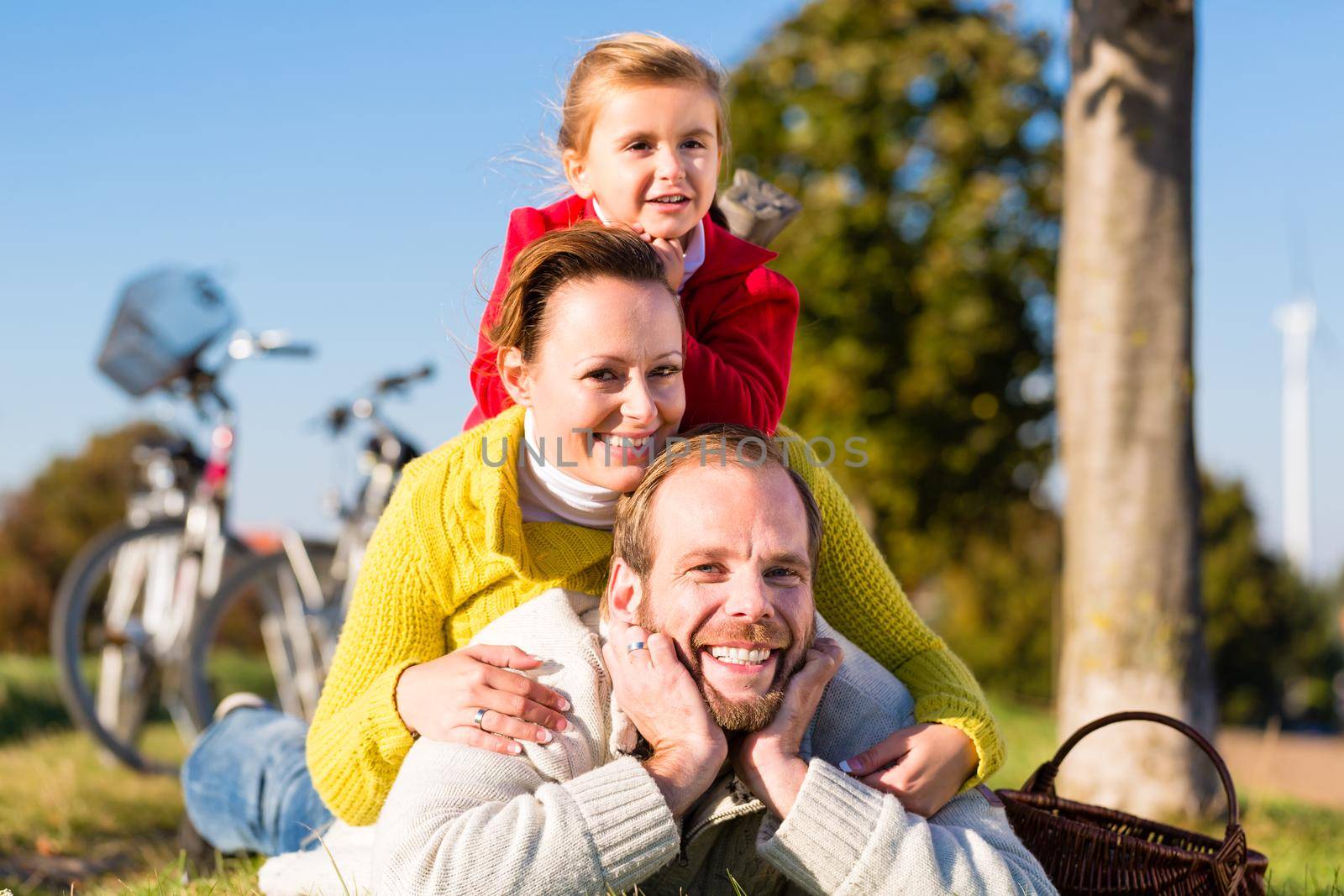 Family with bicycle in park in fall by Kzenon