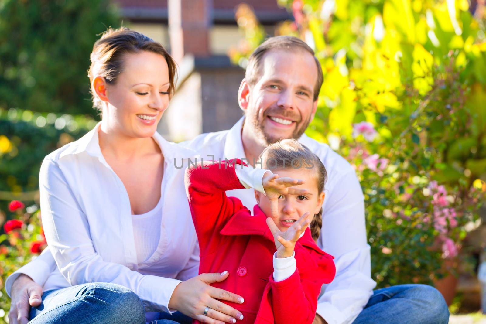 Family with mother, father and daughter together in the garden meadow