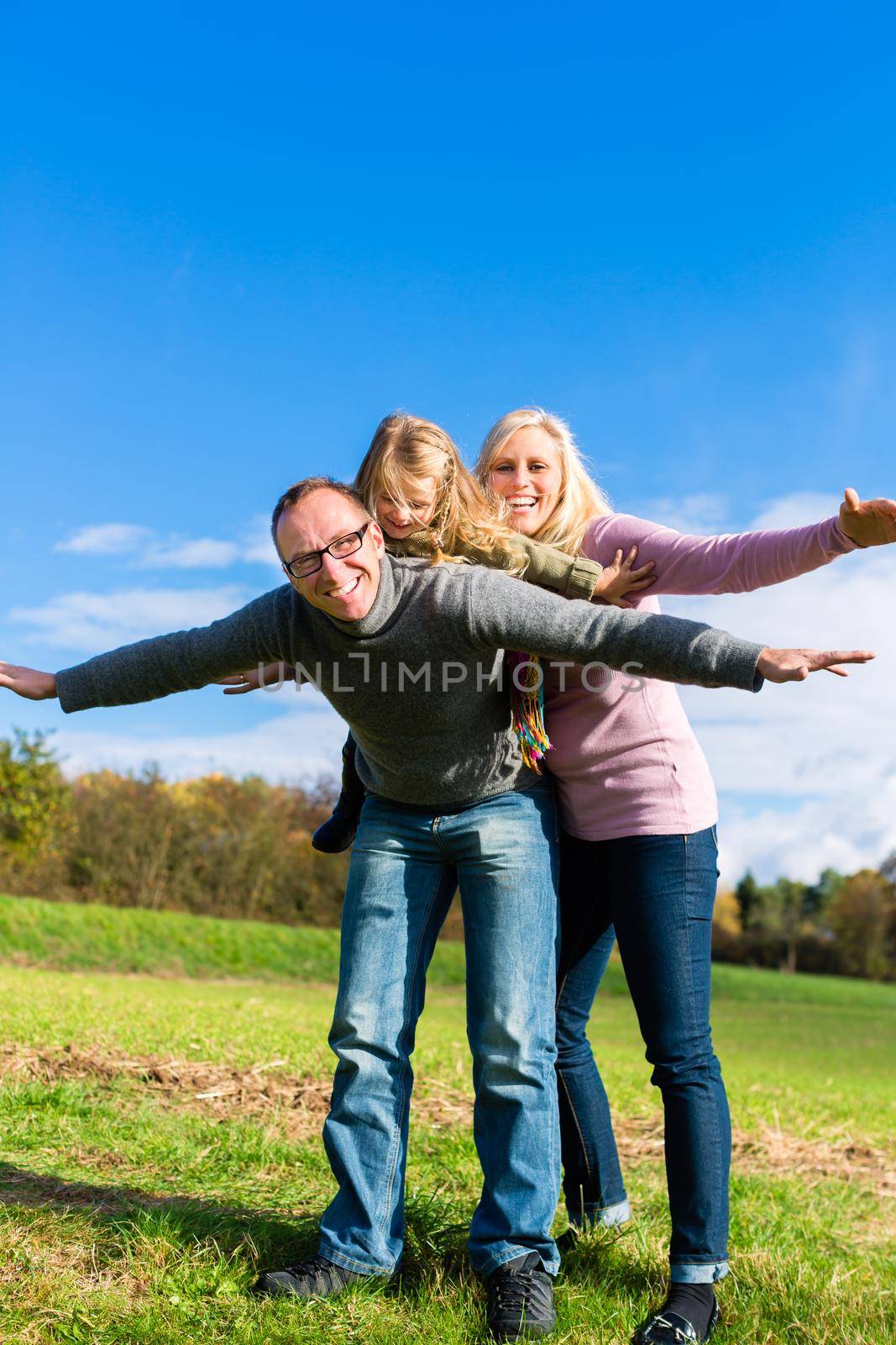 Family playing on meadow in fall or autumn