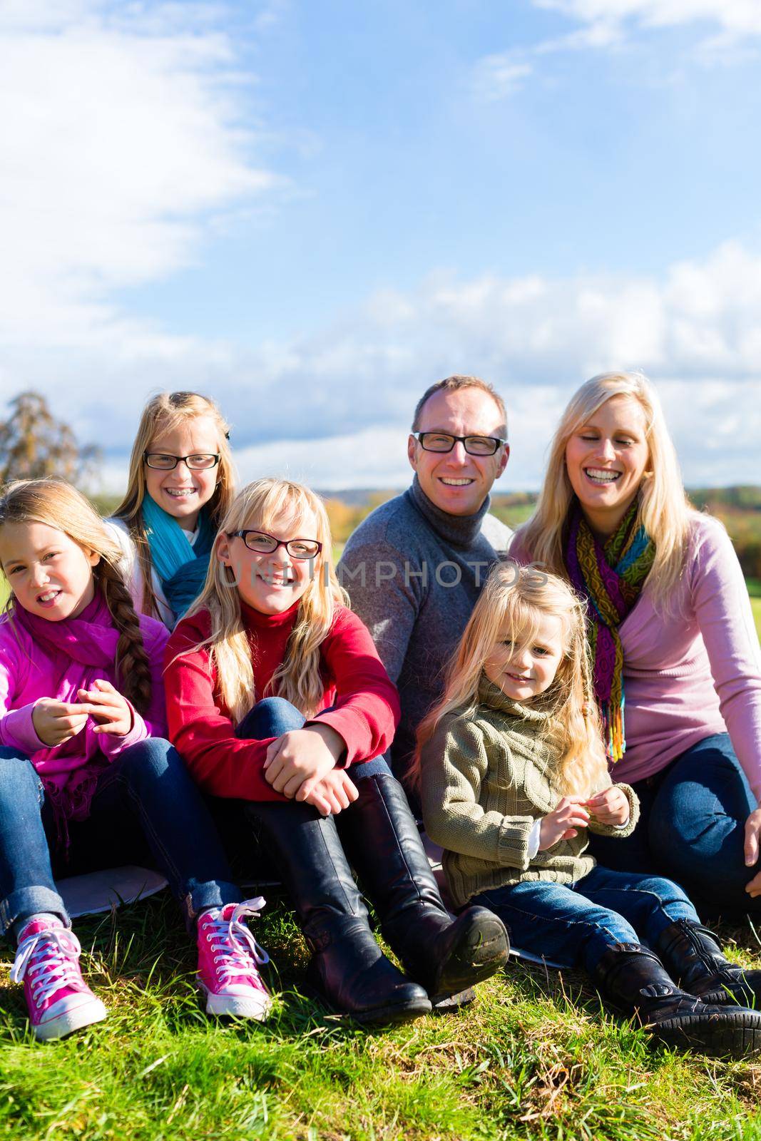 Family sitting on fall or autumn meadow