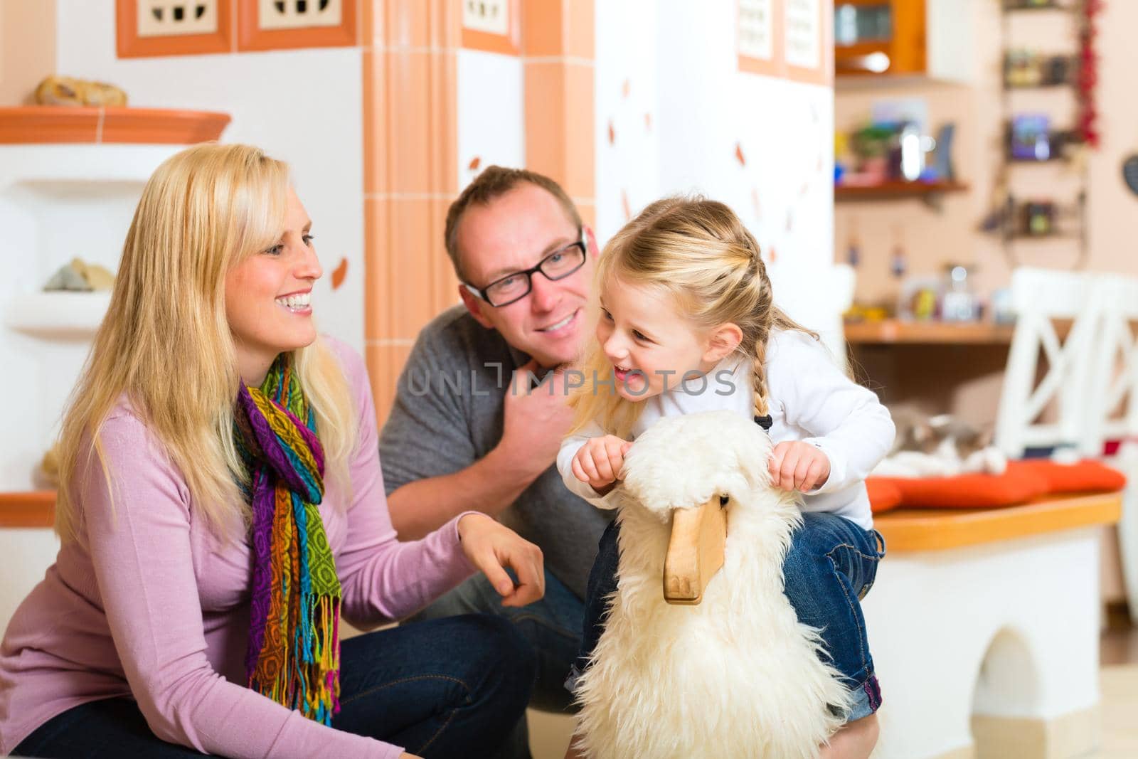 Parents and daughter rocking and playing with rocker horse in living room