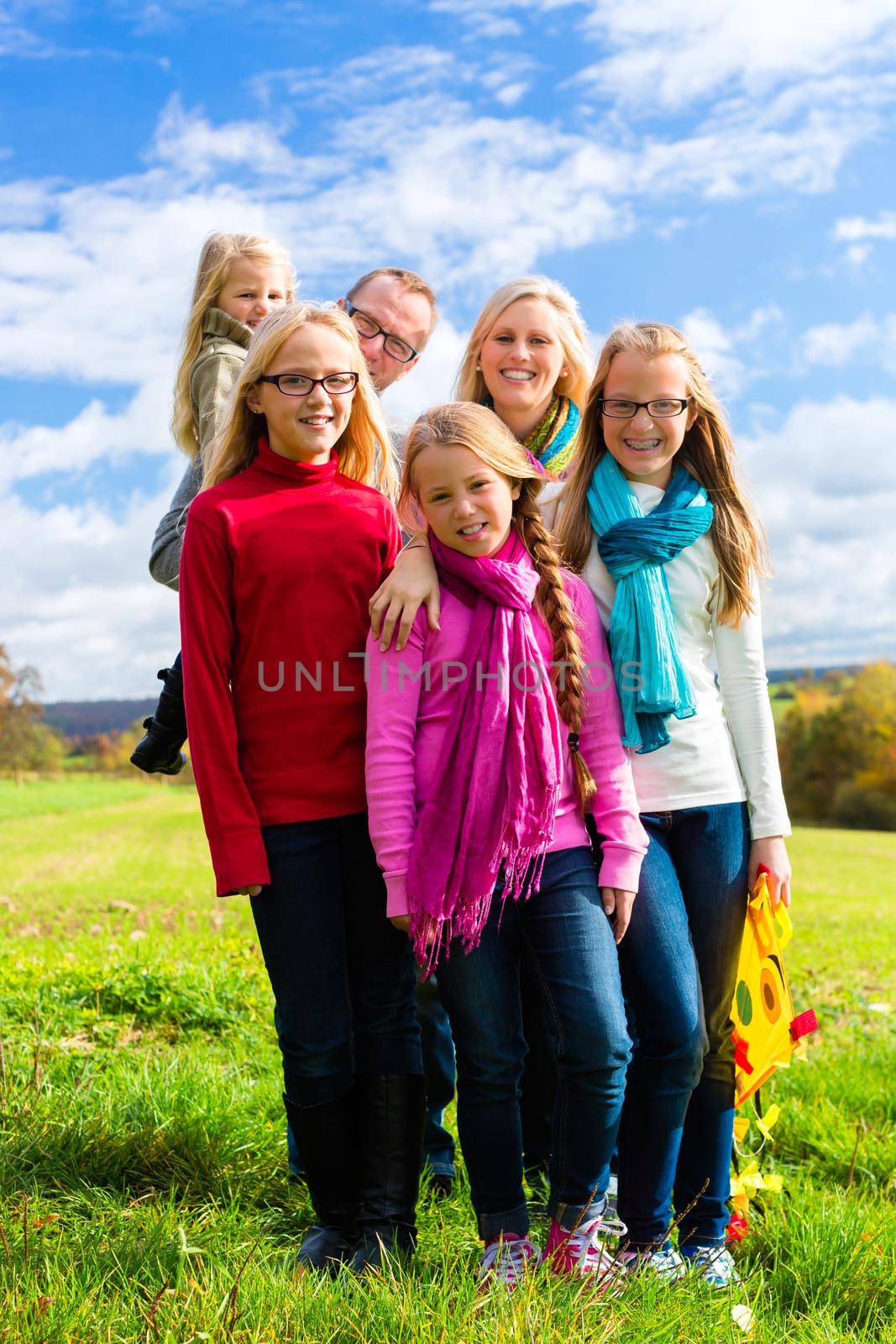 Family walking through the park in fall or autumn by Kzenon