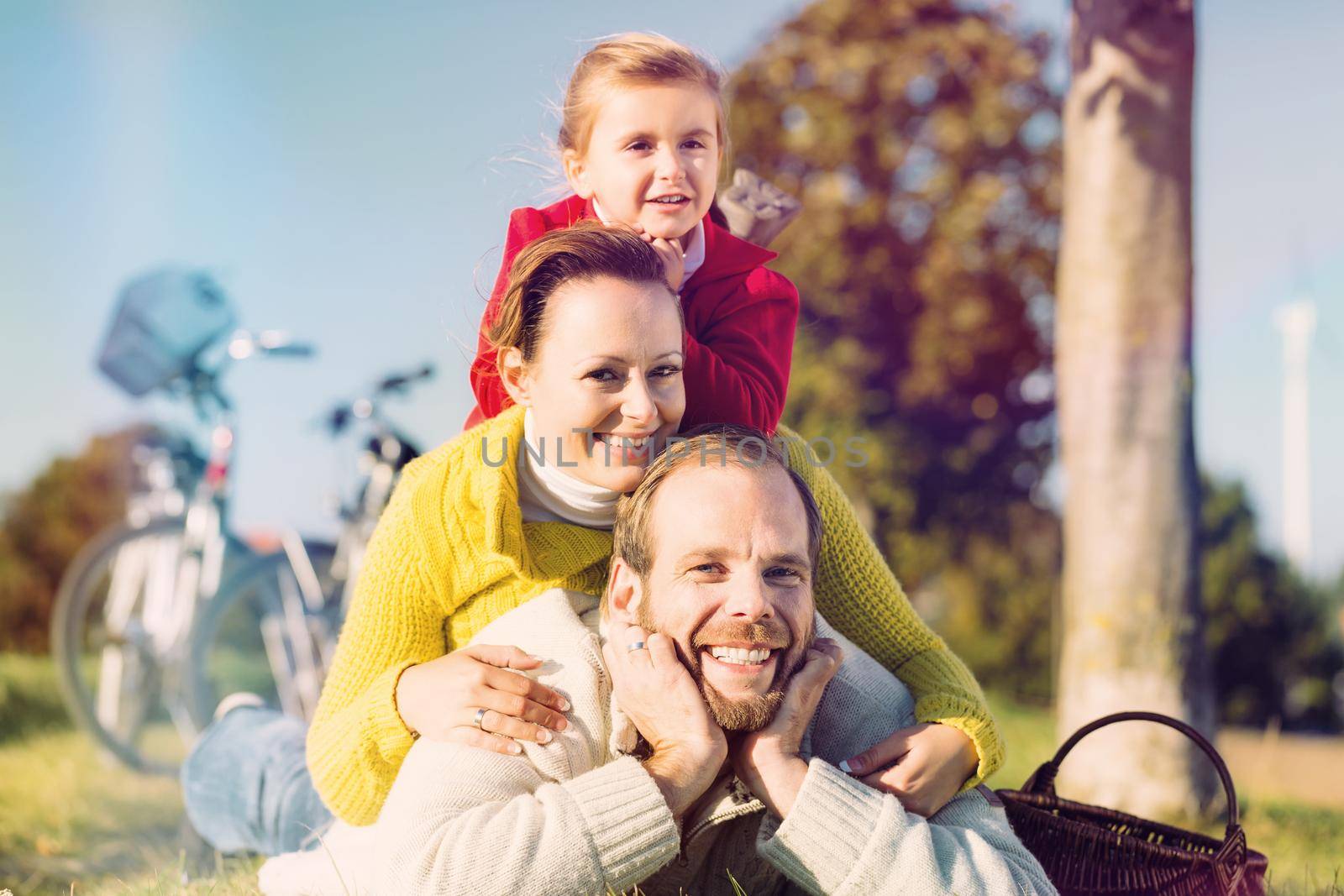 Family with bicycle in park in fall by Kzenon