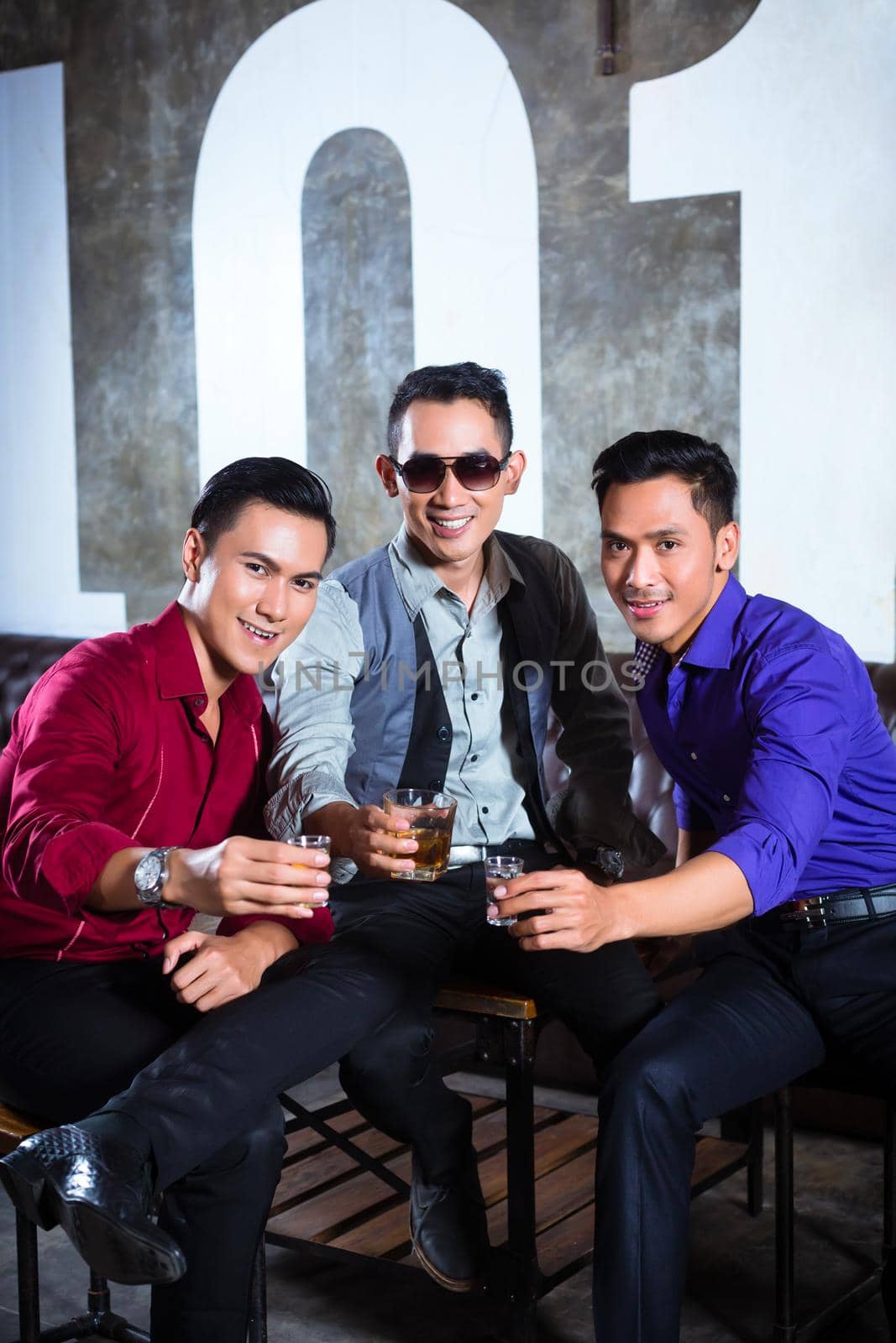 Asian young and handsome group of party people or male friends drinking shots in fancy night club