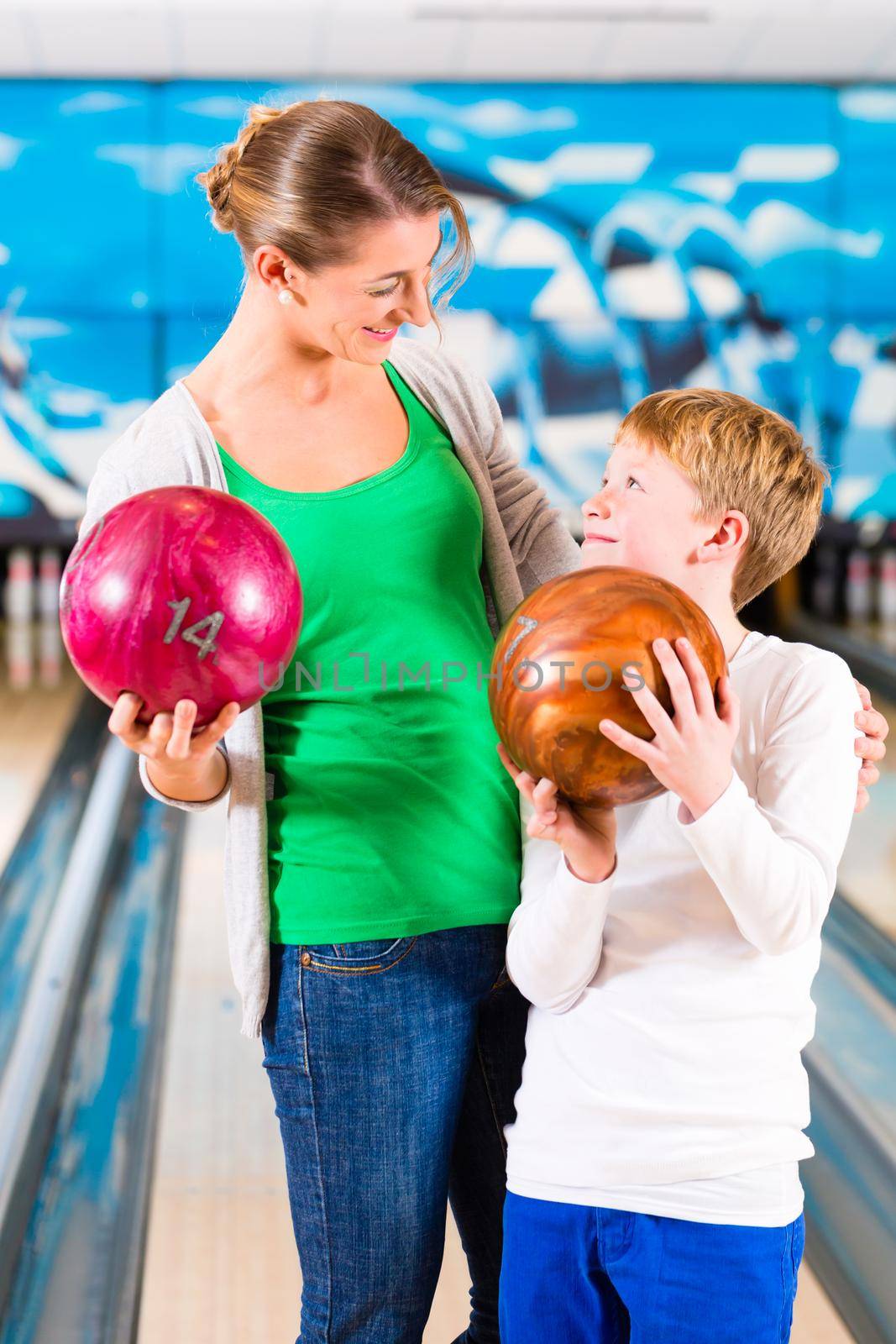 Mother and son playing together at bowling center by Kzenon