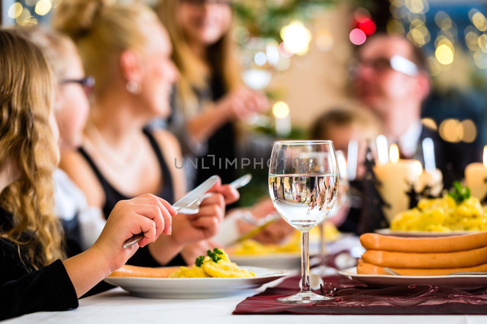 Family of Mother, father, children celebrating Christmas eve with traditional dinner Wiener sausages and potato salad