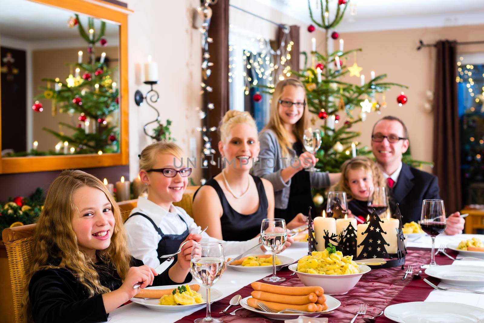Family having Christmas dinner sausages by Kzenon
