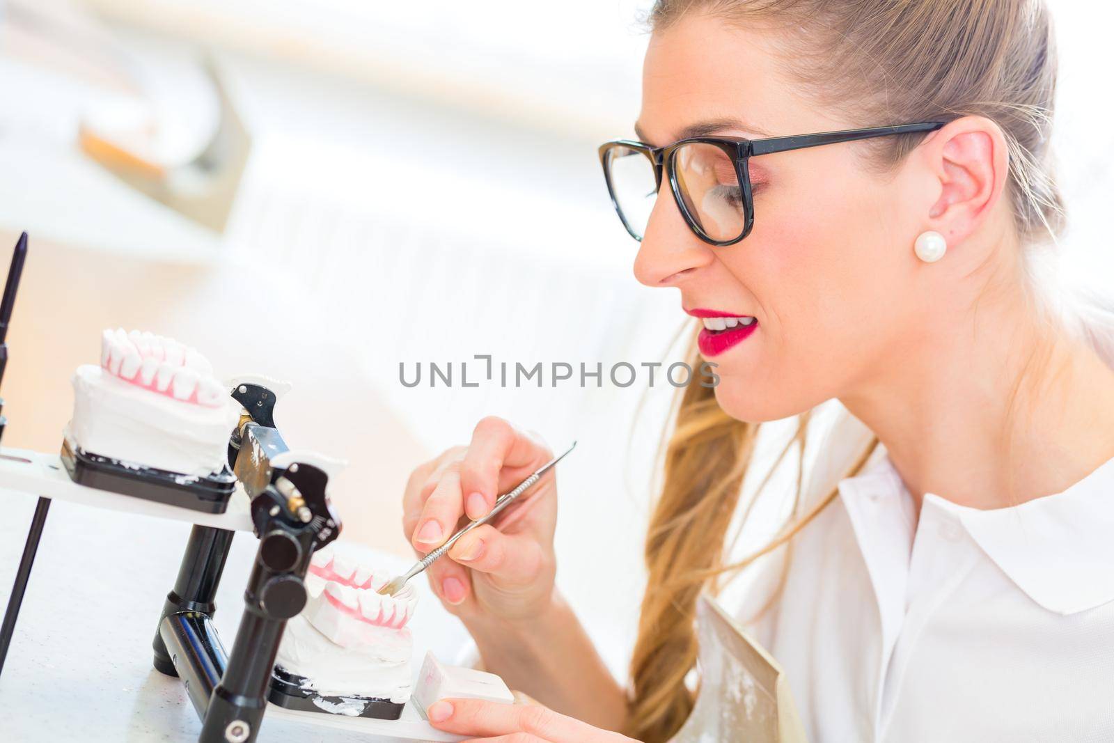 Female dental technician or orthodontist producing denture with imprint