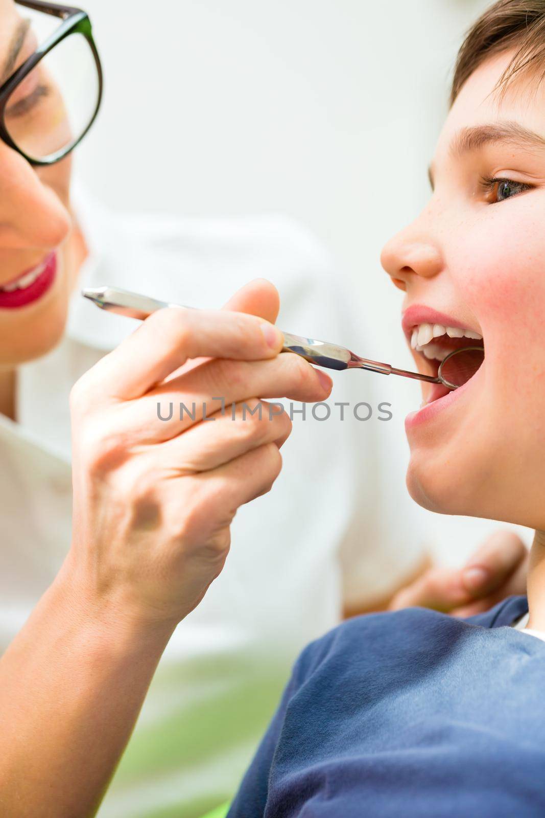 Dentist giving patient advice in dental surgery by Kzenon