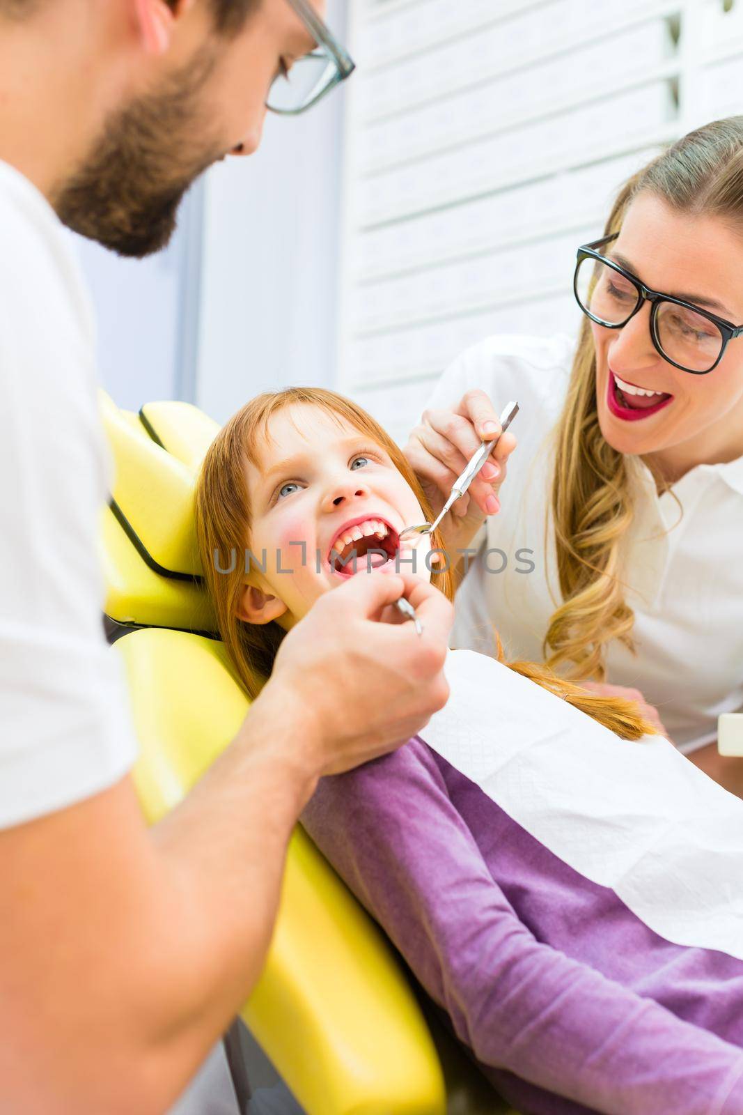 Dentist giving girl treatment in dental surgery by Kzenon