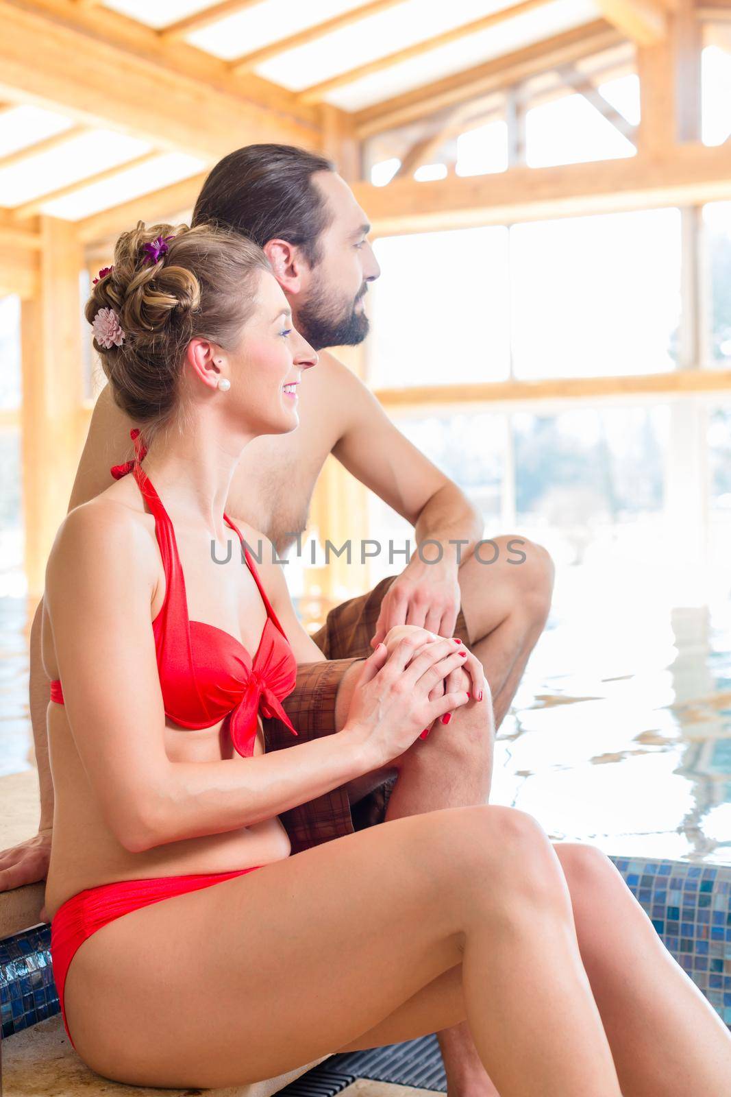 Couple relaxing together at wellness spa pool by Kzenon