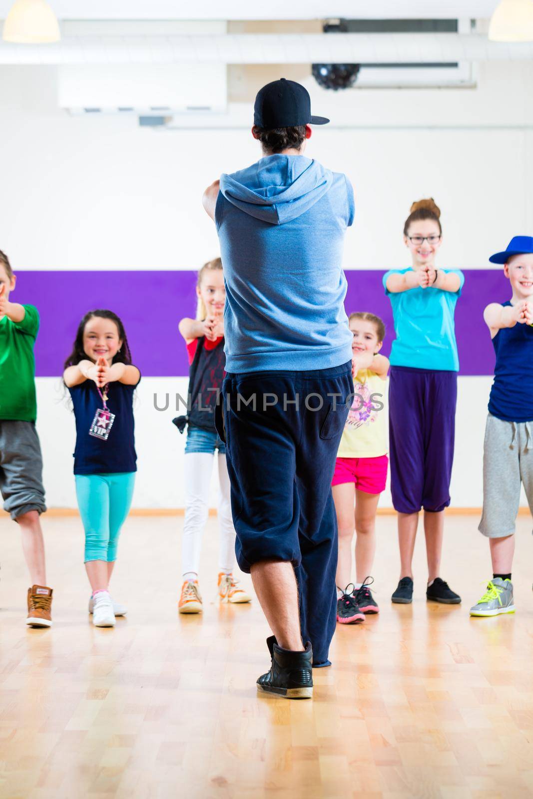 Dance teacher giving kids Zumba fitness class by Kzenon