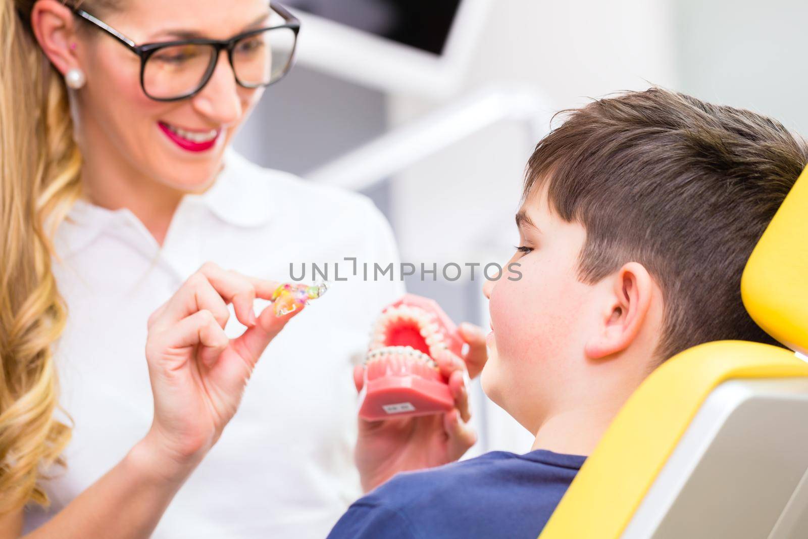 Female Orthodontist explaining boy braces by Kzenon