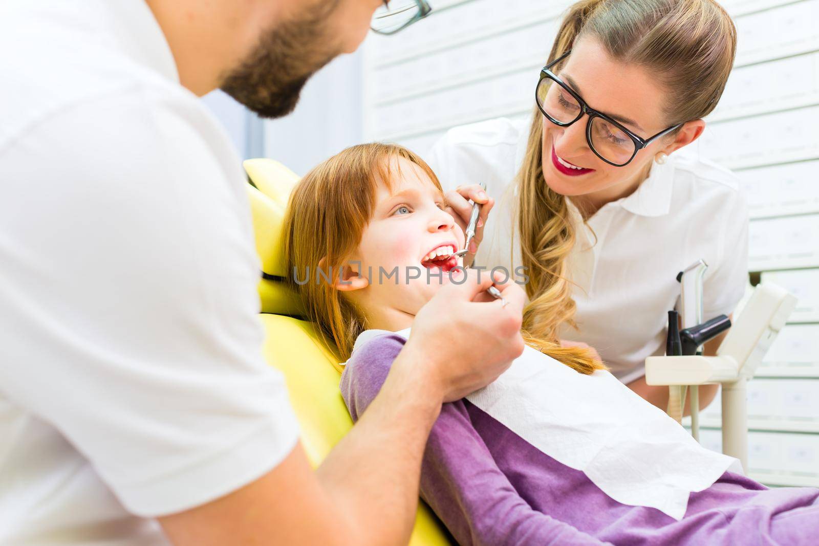 Dentist giving girl treatment in dental surgery