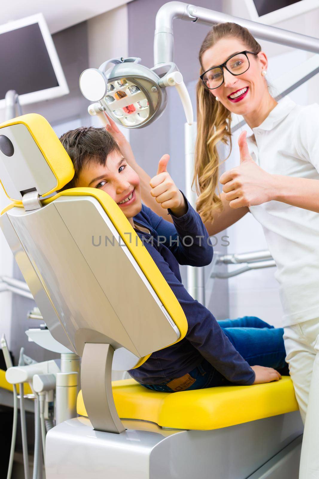 Dentist giving boy advice in dental surgery by Kzenon