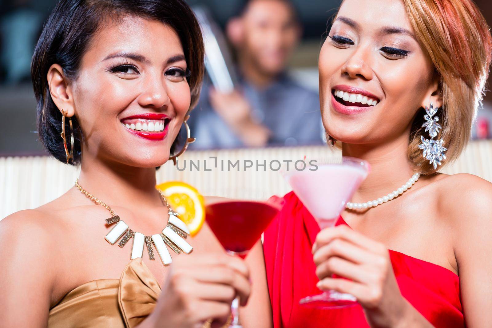 Asian women drinking cocktails in fancy bar