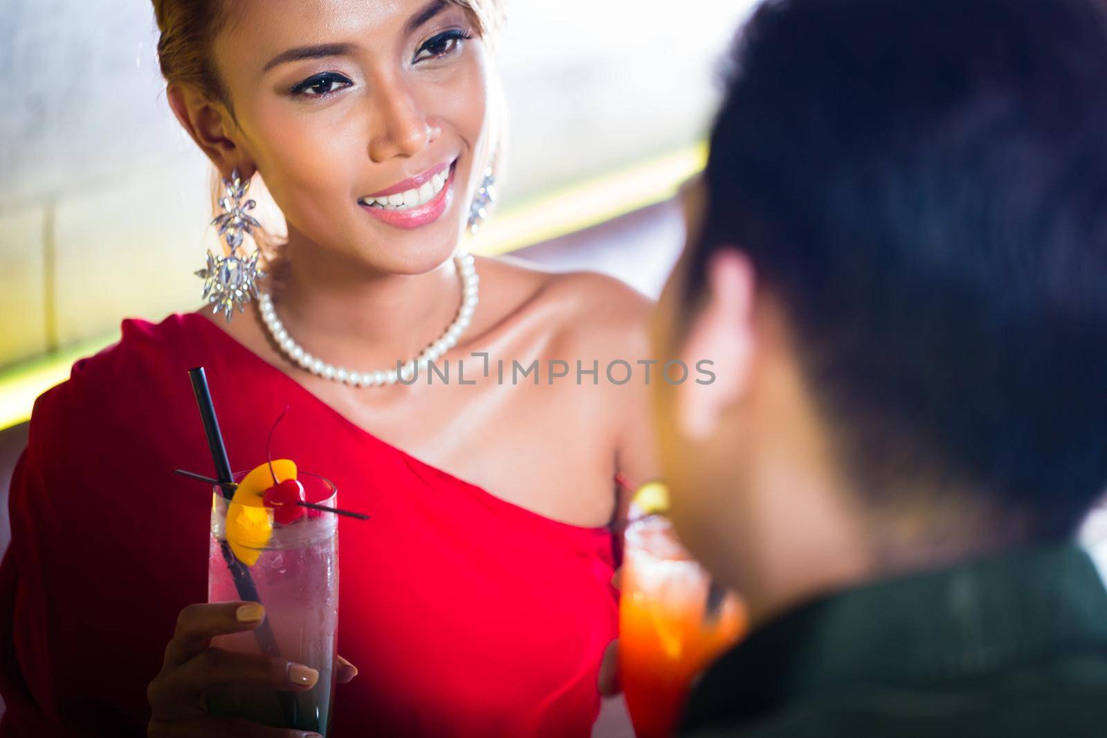 Asian couple drinking cocktails in fancy bar