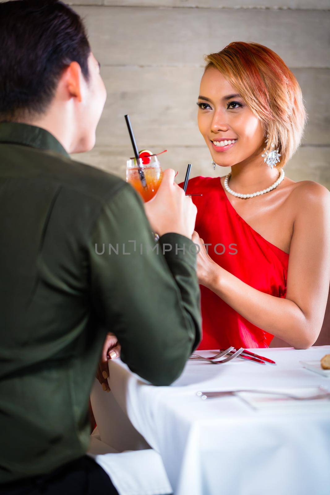 Asian couple drinking cocktails in fancy bar