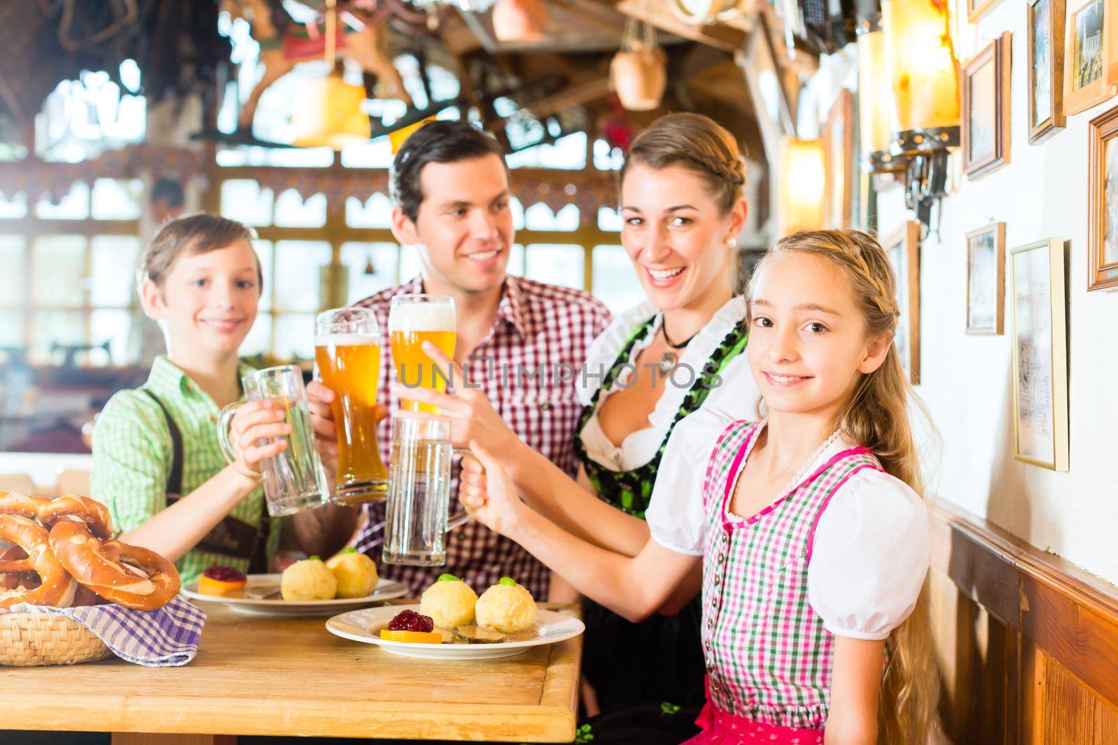 Bavarian girl wearing dirndl and eating with family in traditional restaurant