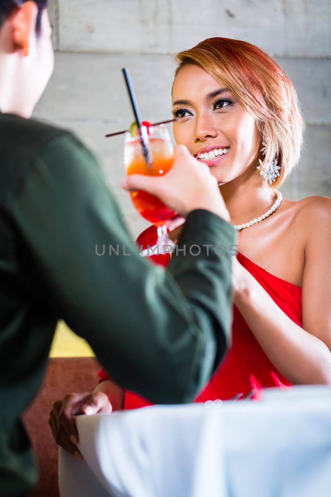 Asian couple drinking cocktails in fancy bar