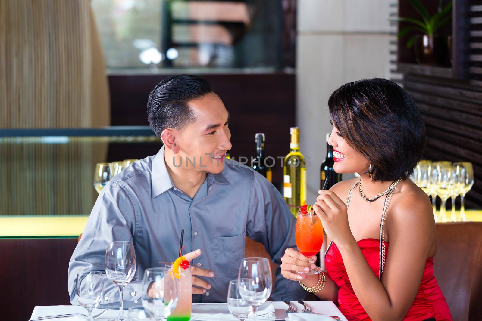Asian couple drinking cocktails in fancy bar by Kzenon