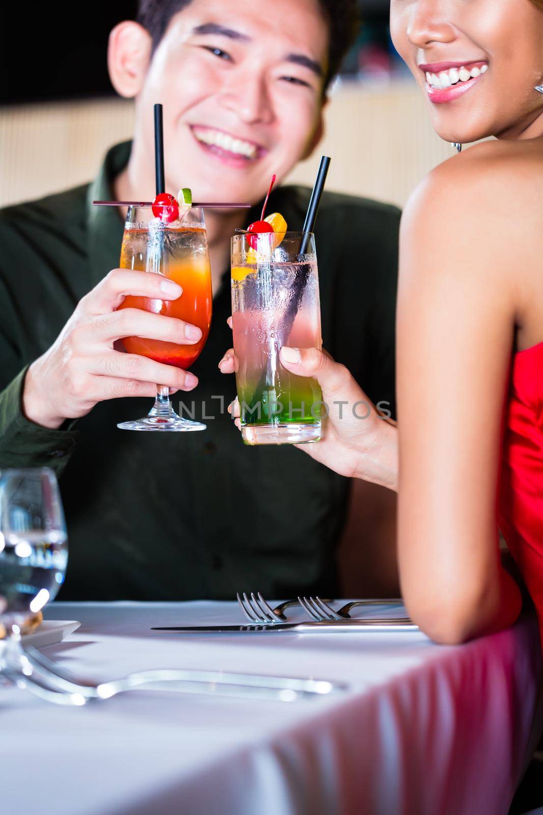 Asian couple drinking cocktails in fancy bar by Kzenon
