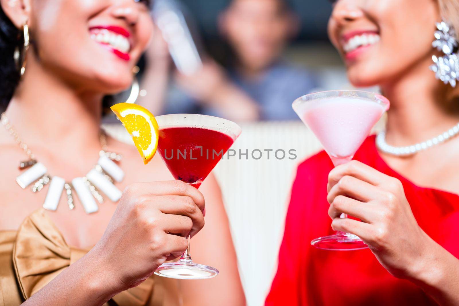 Asian women drinking cocktails in fancy bar