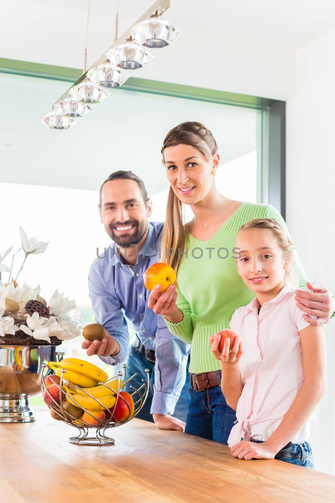Mother, father, child picking fresh fruits for healthy living in home kitchen