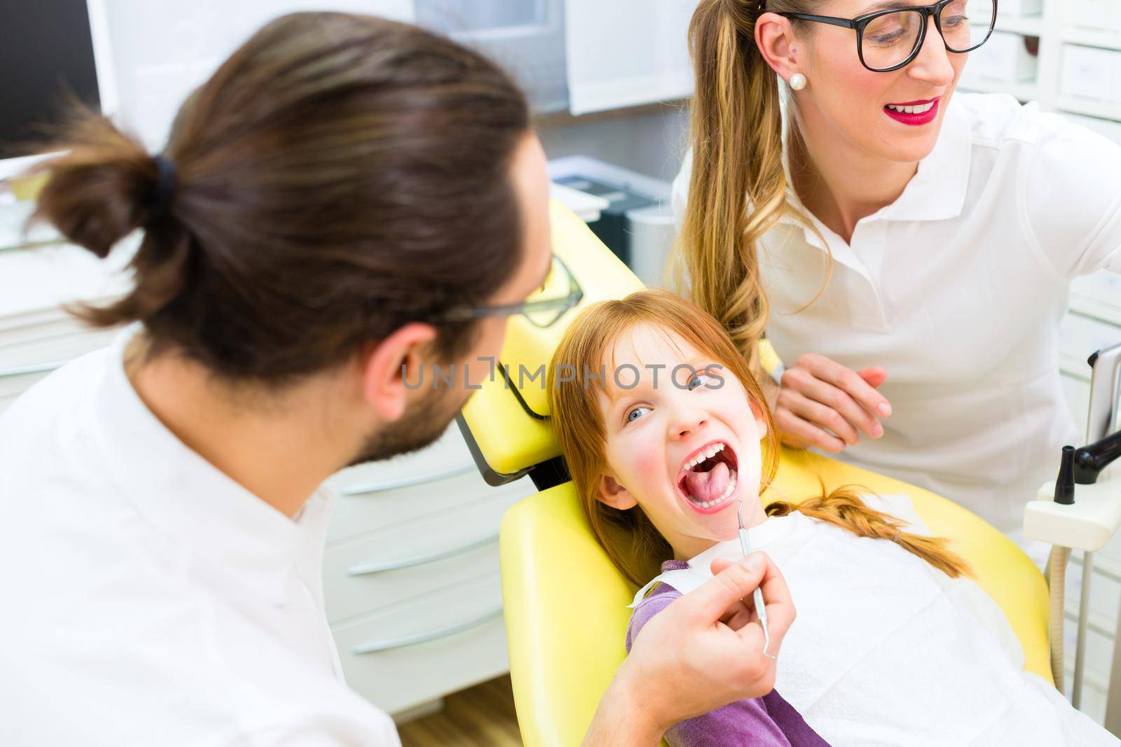 Dentist giving girl treatment in dental surgery