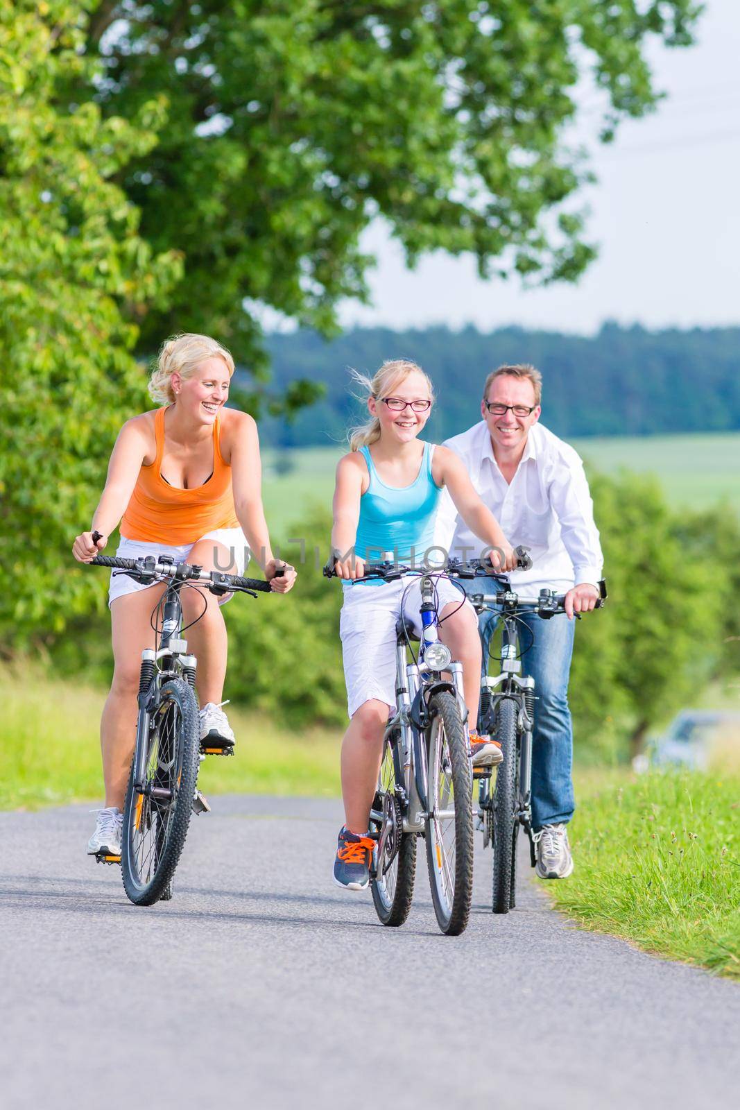 Parents and daughter have bicycle or bike tour on country lane