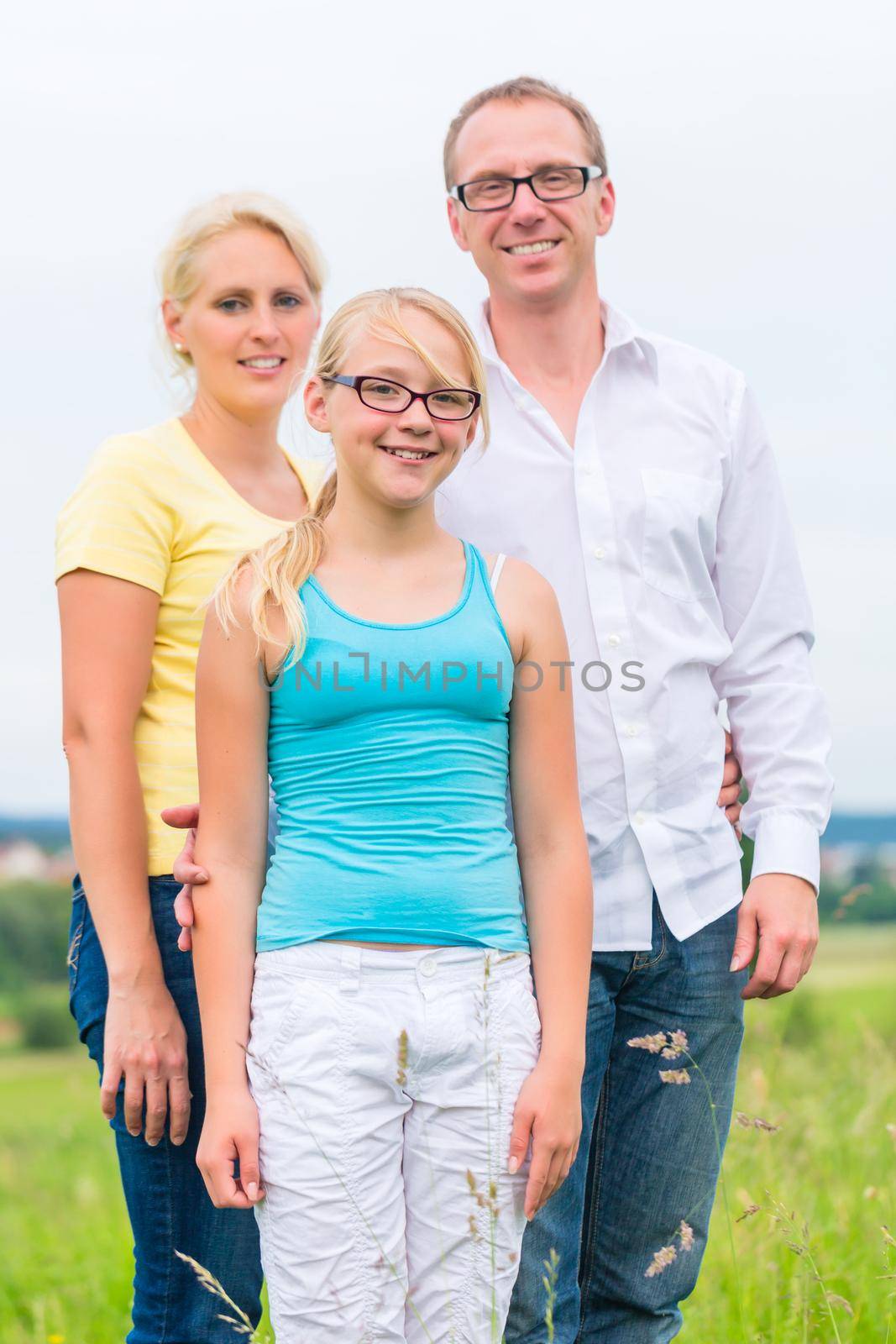 Parents and daughter standing on grass of lawn or field
