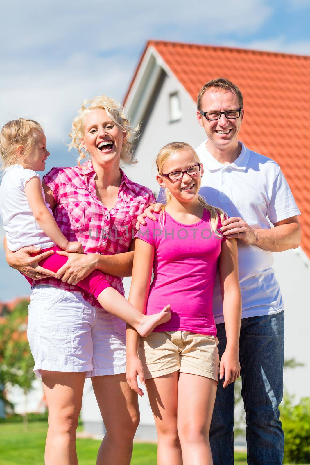 Family of Parents and children standing proud in front of home