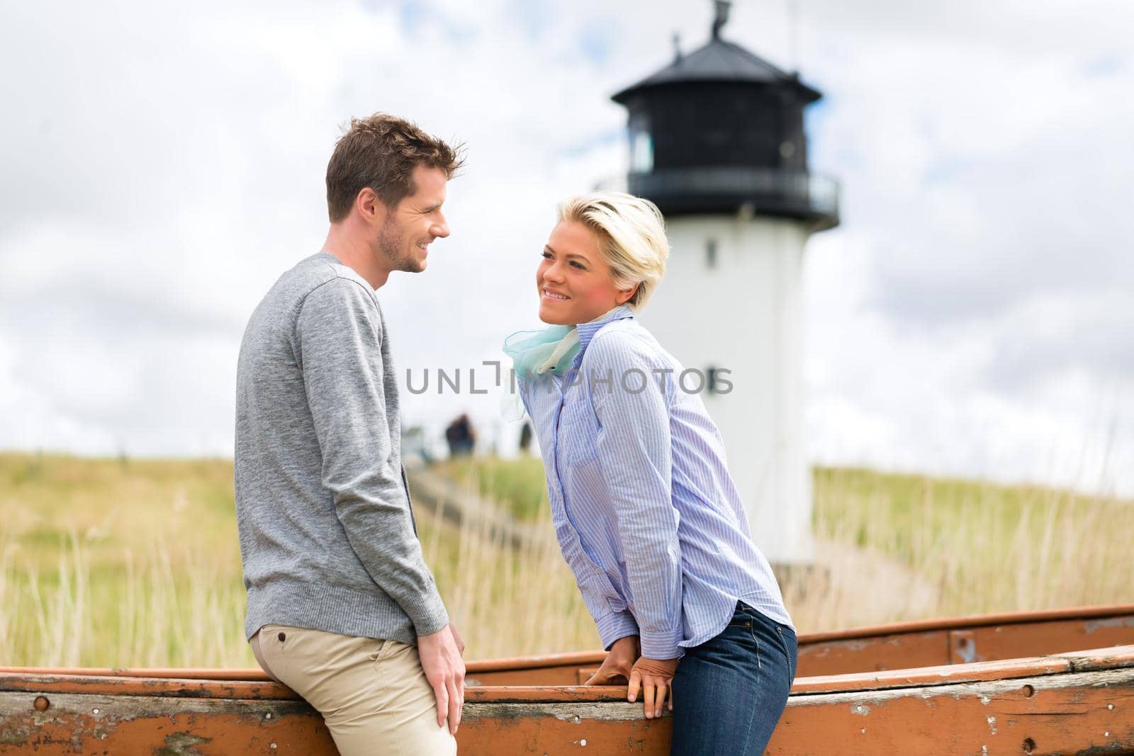Couple having romantic vacation in German north sea beach dune in front of lighthouse