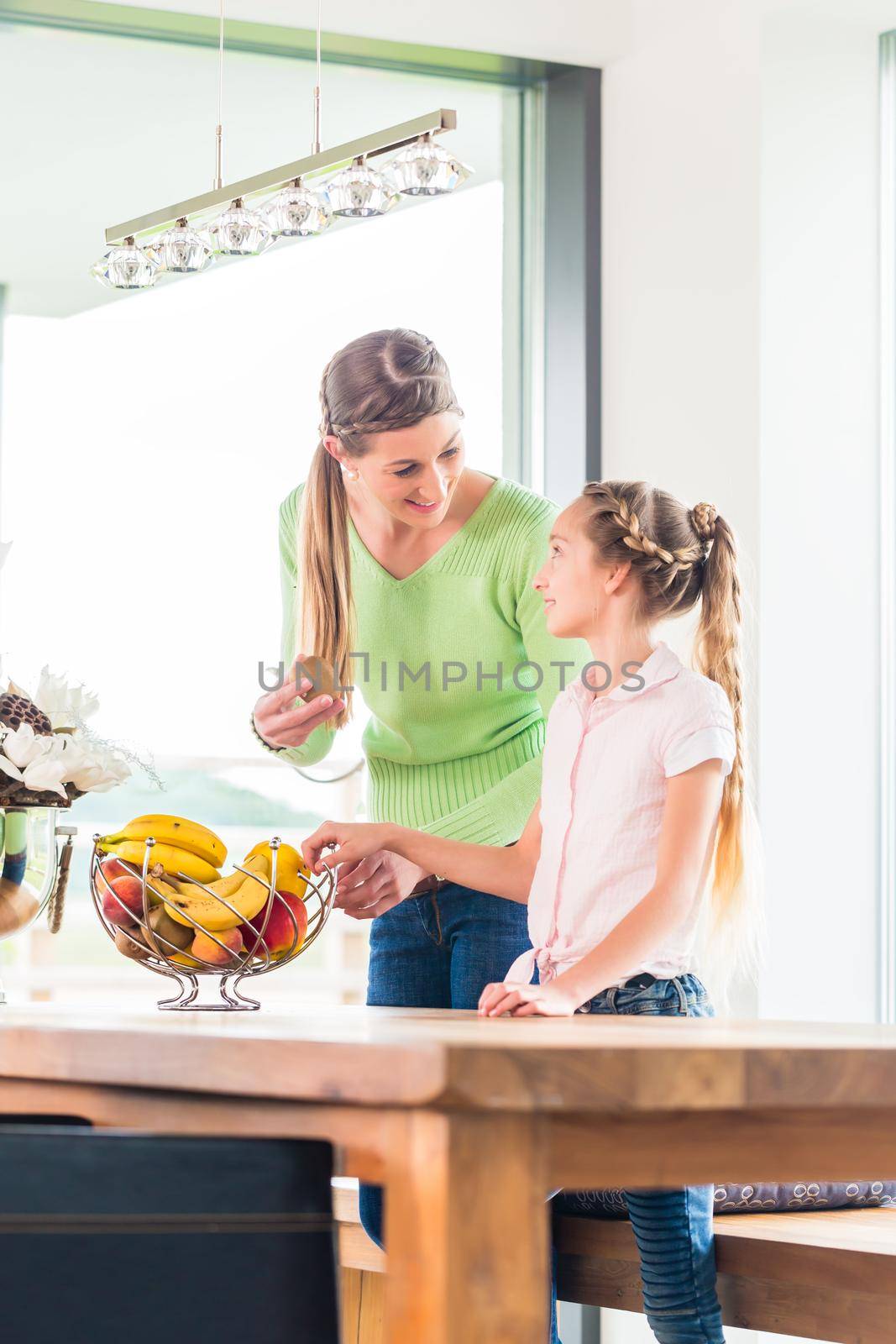 Mother giving child fresh fruits for healthy living in home kitchen