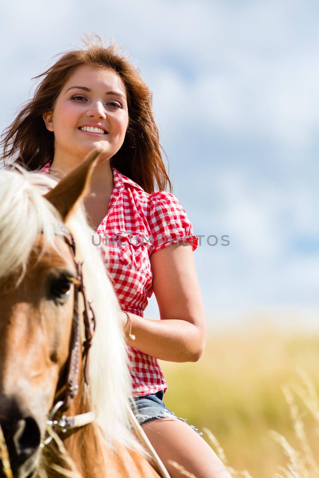 Woman riding on horse in summer meadow by Kzenon