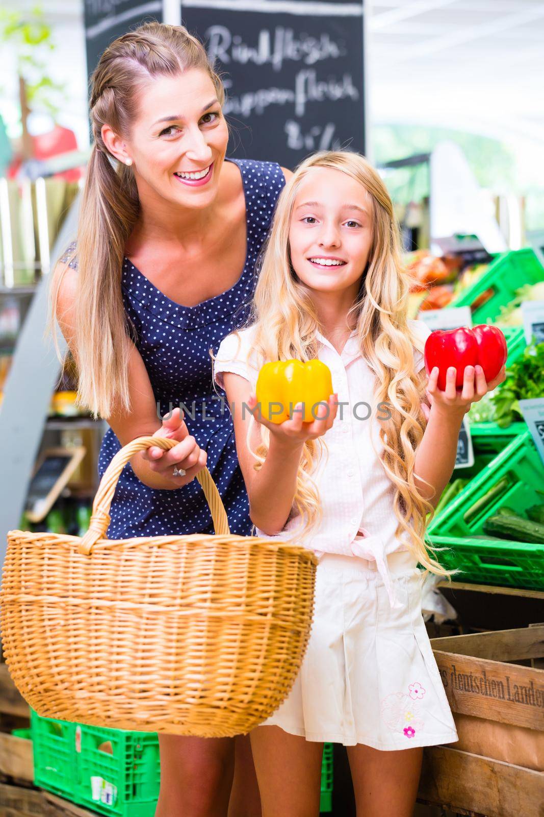 Mother and daughter selecting vegetables while grocery shopping in organic supermarket