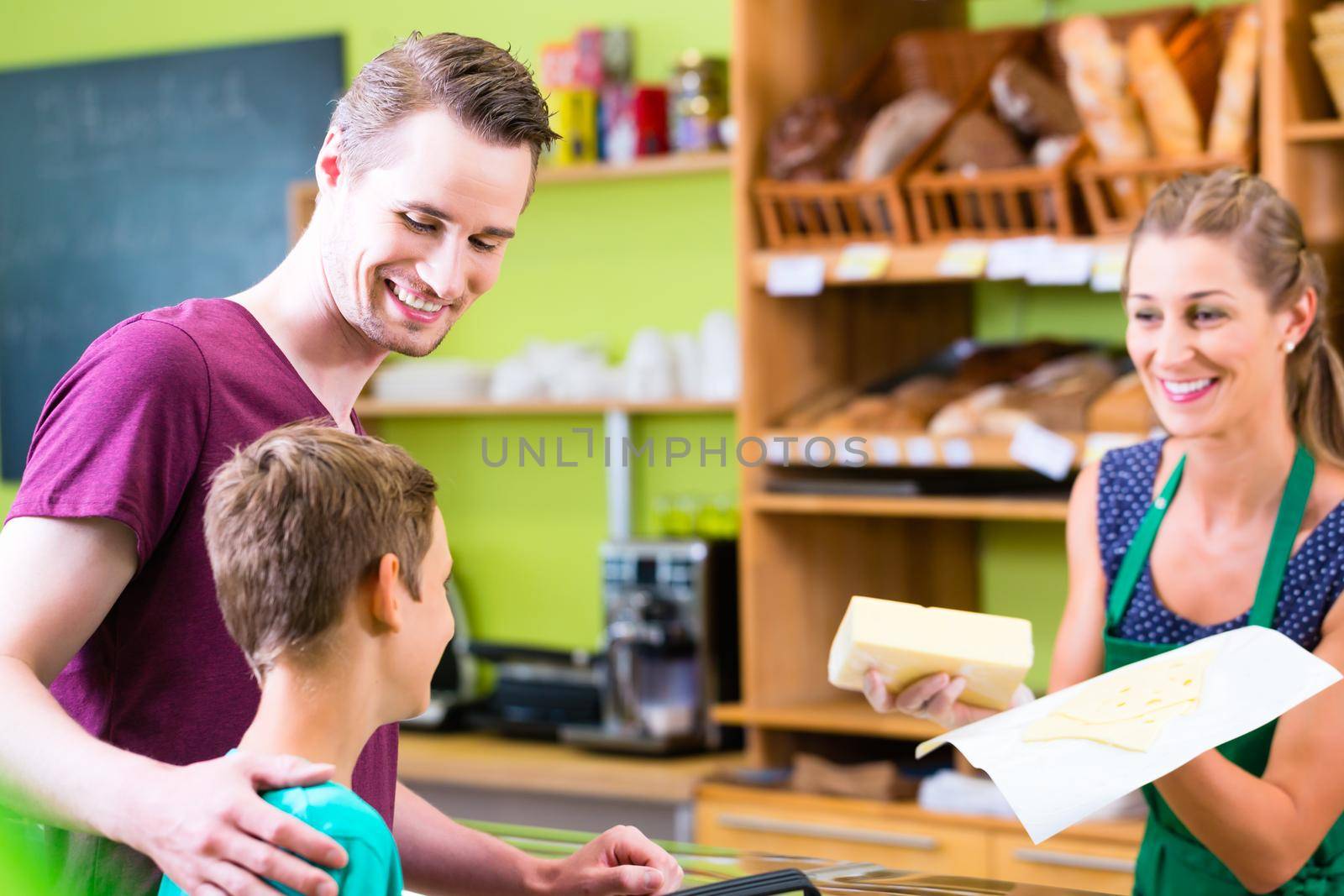 Father and son buying cheese at organic supermarket counter