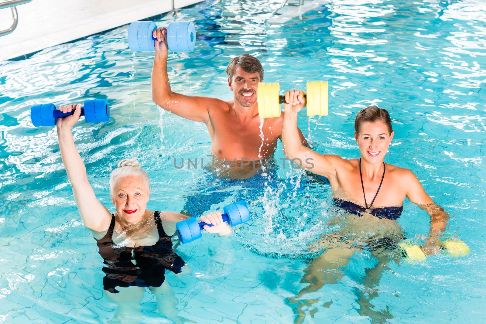 Group of people, mature man, young and senior women, at water gymnastics or aquarobics